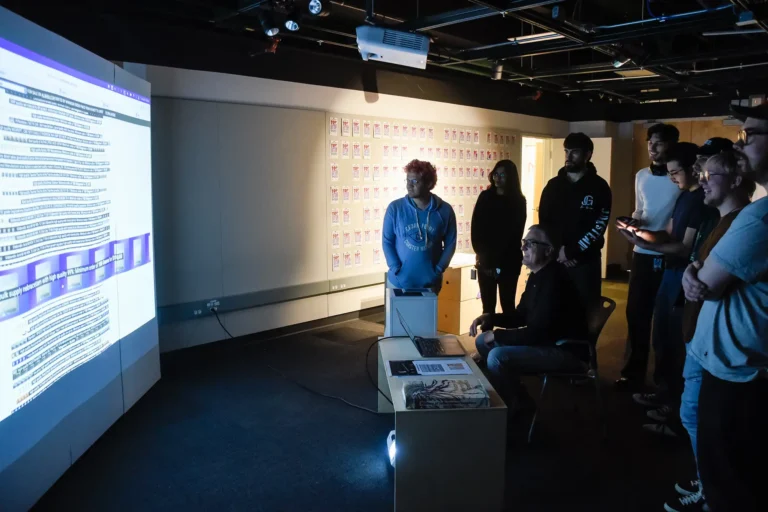 Professor works with students reviewing an interactive design project.