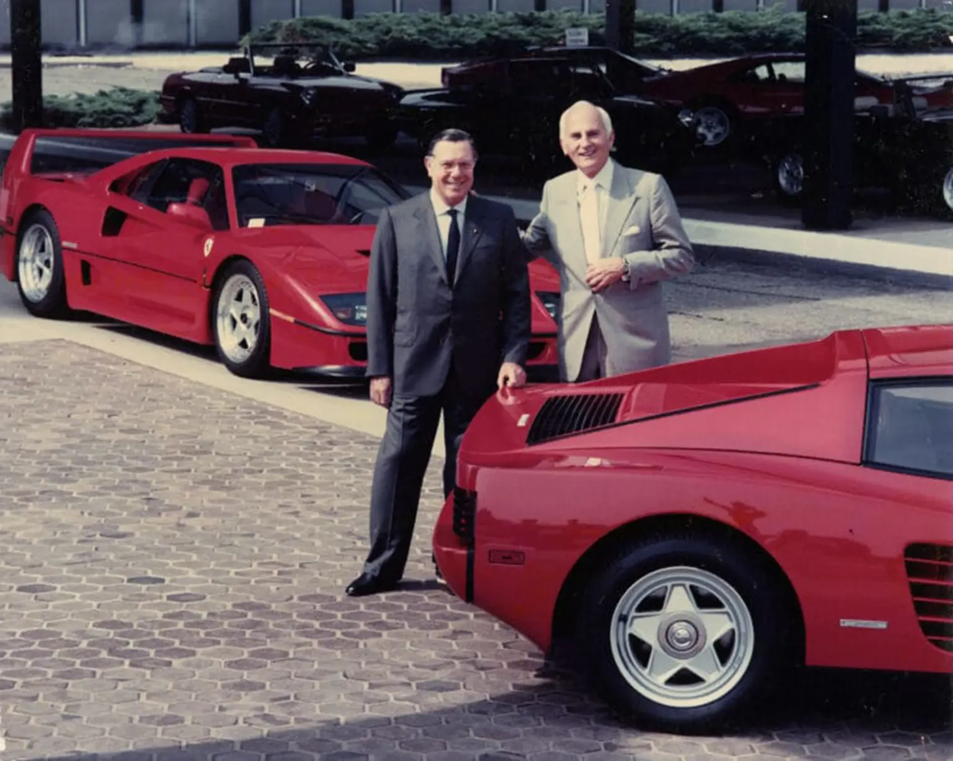Two people standing next to 2 red Ferrari F40's