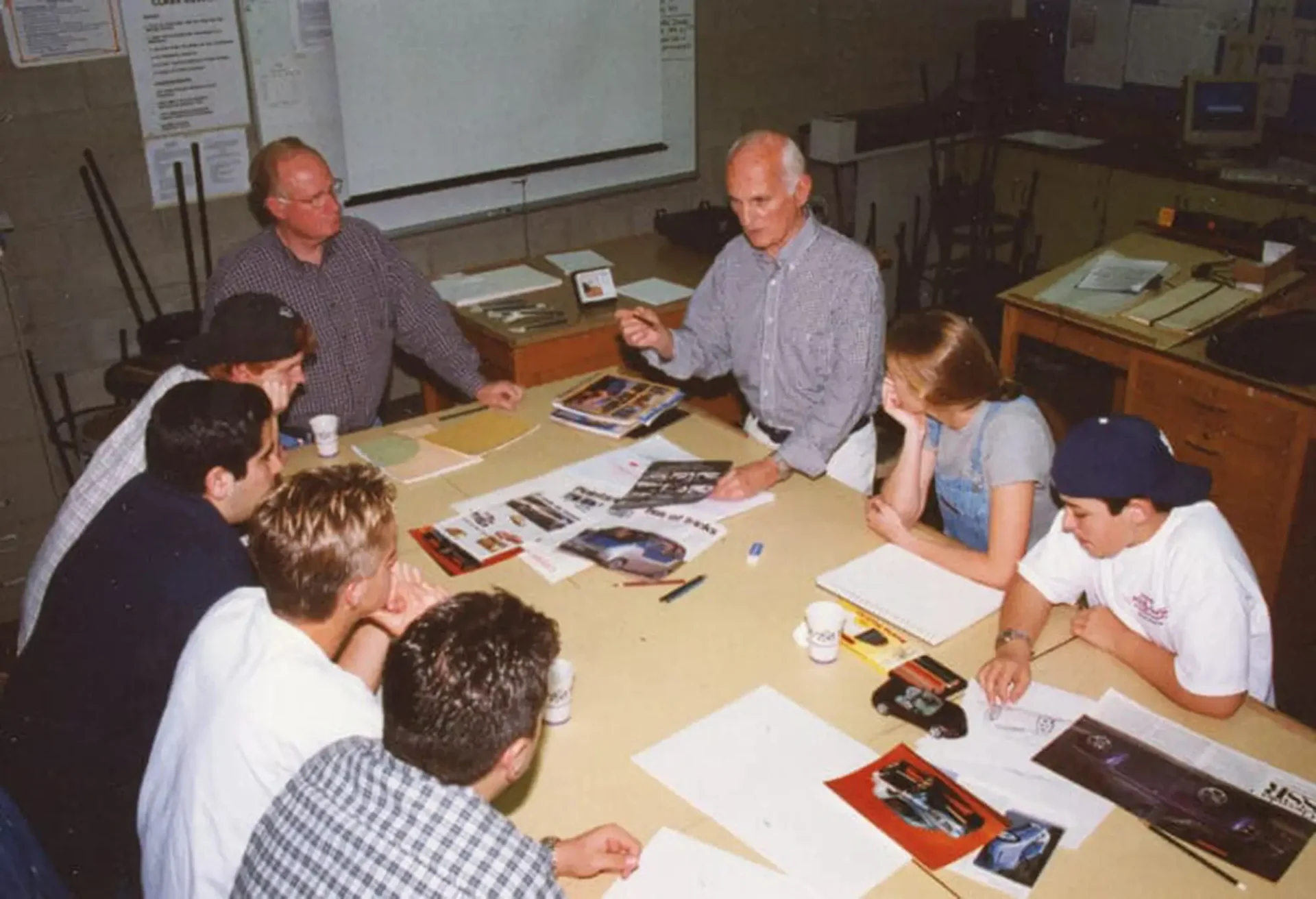 A group of people around a table, going over sketches, images and briefs