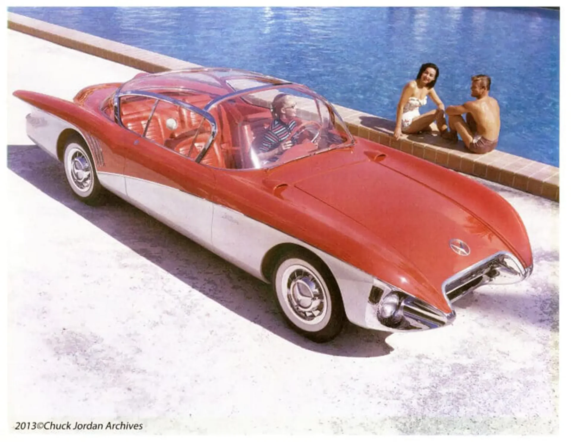 A red sports car parked next to a pool. A man and woman are looking at the car, sitting on the edge of the pool