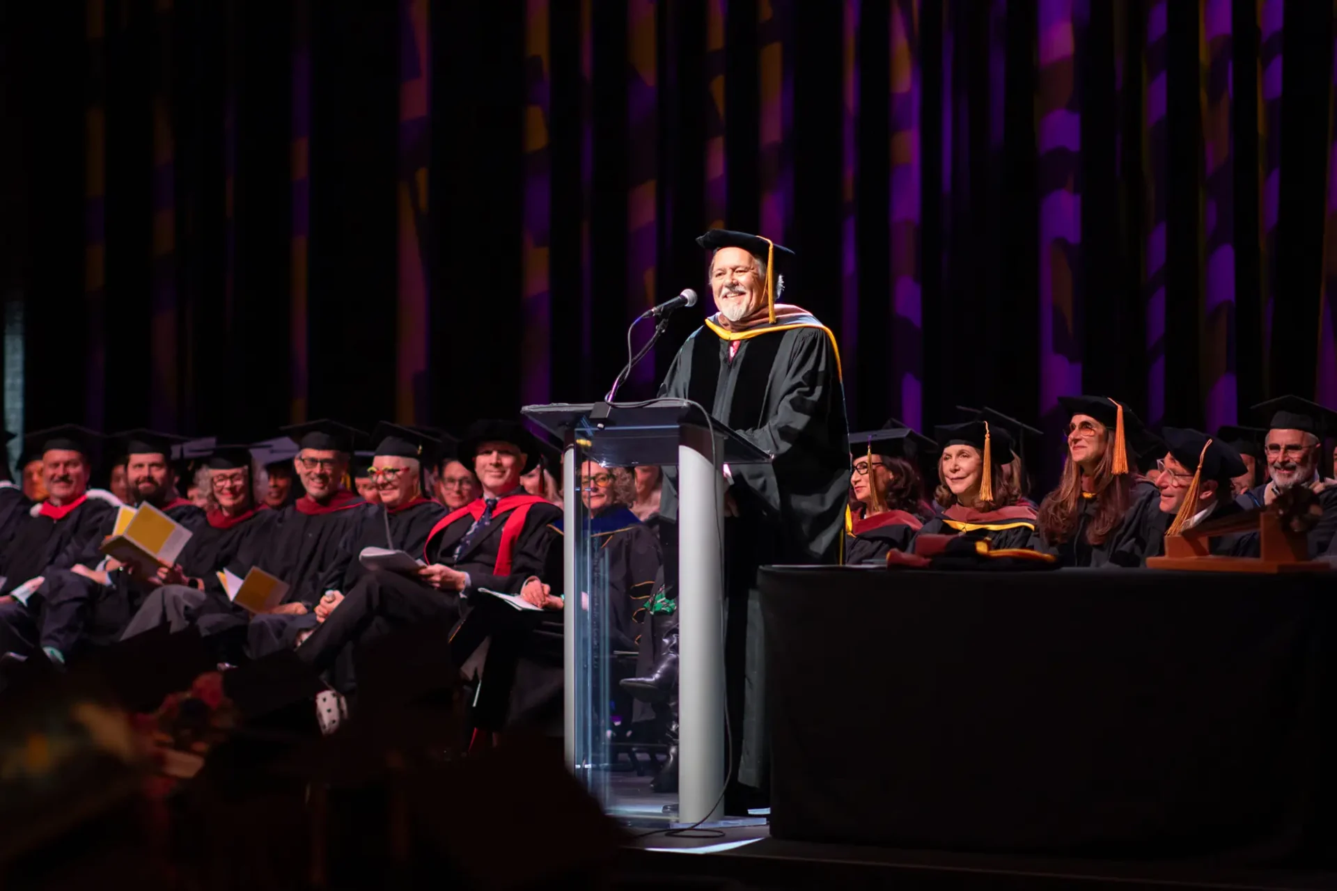 A commencement speaker smiling at the podium