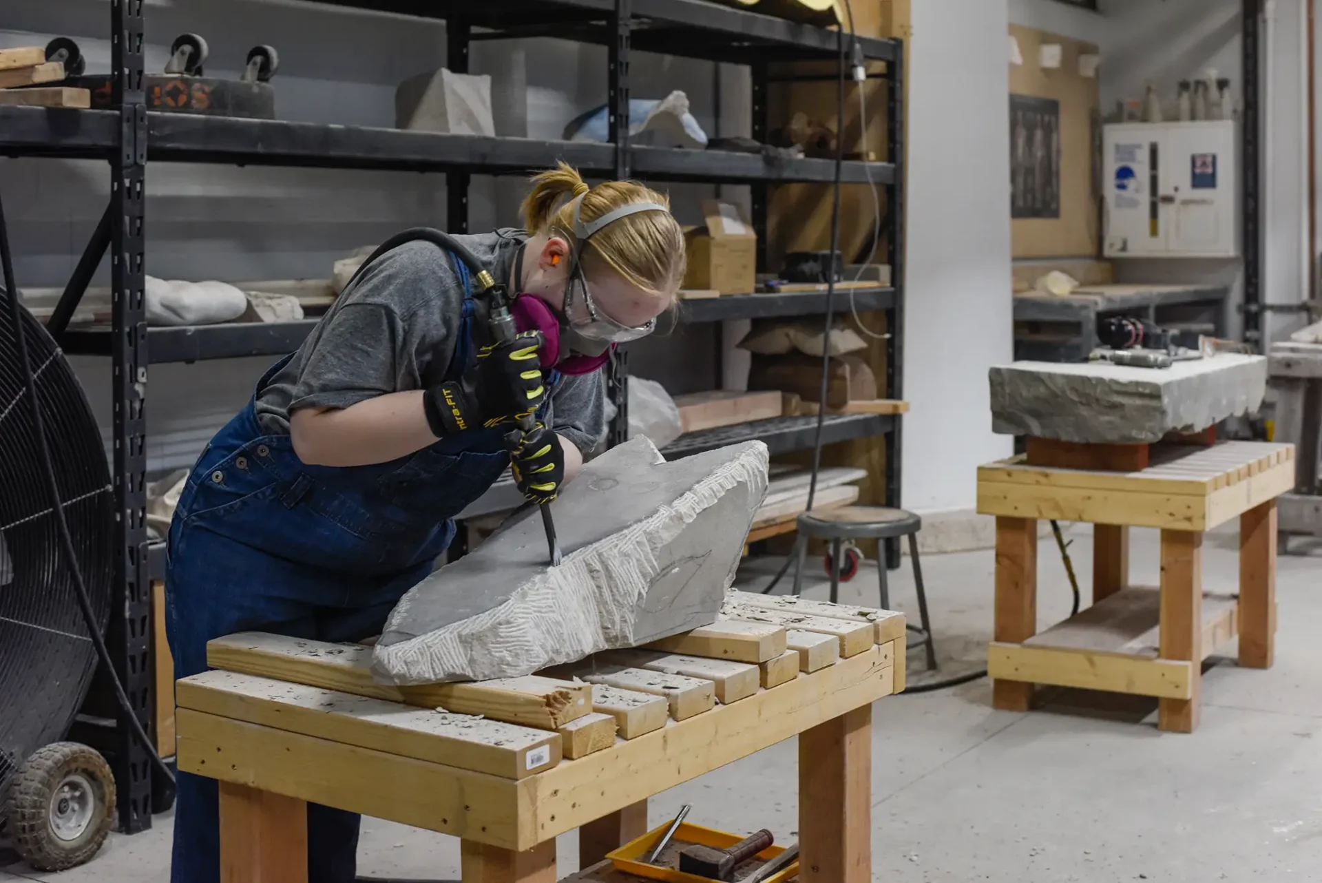 Student sculpting in stone in the sculpture studio.