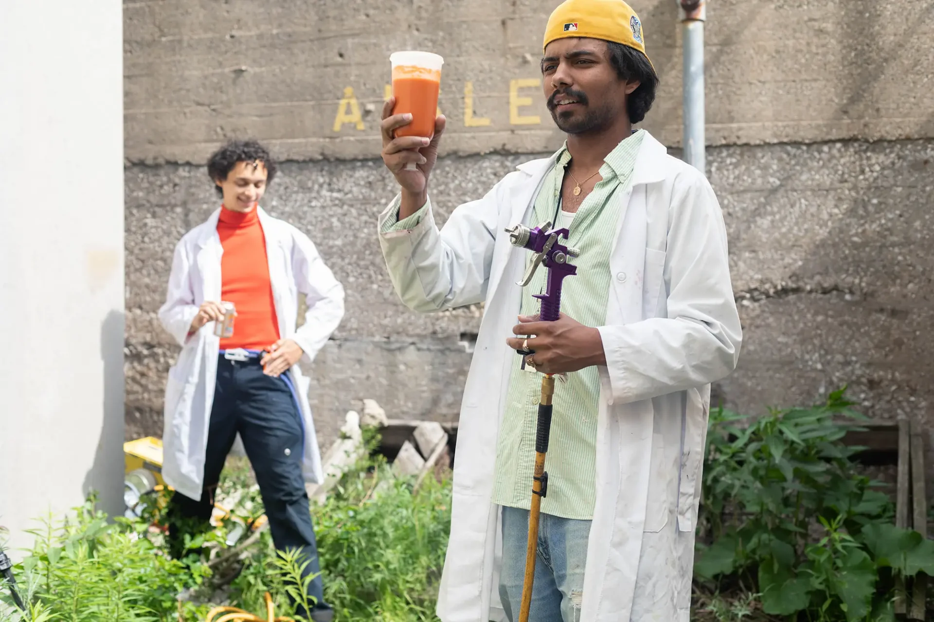 Two students wearing white lab coats demonstrating their method for creating sustainable spray paint from upscaling food waste streams