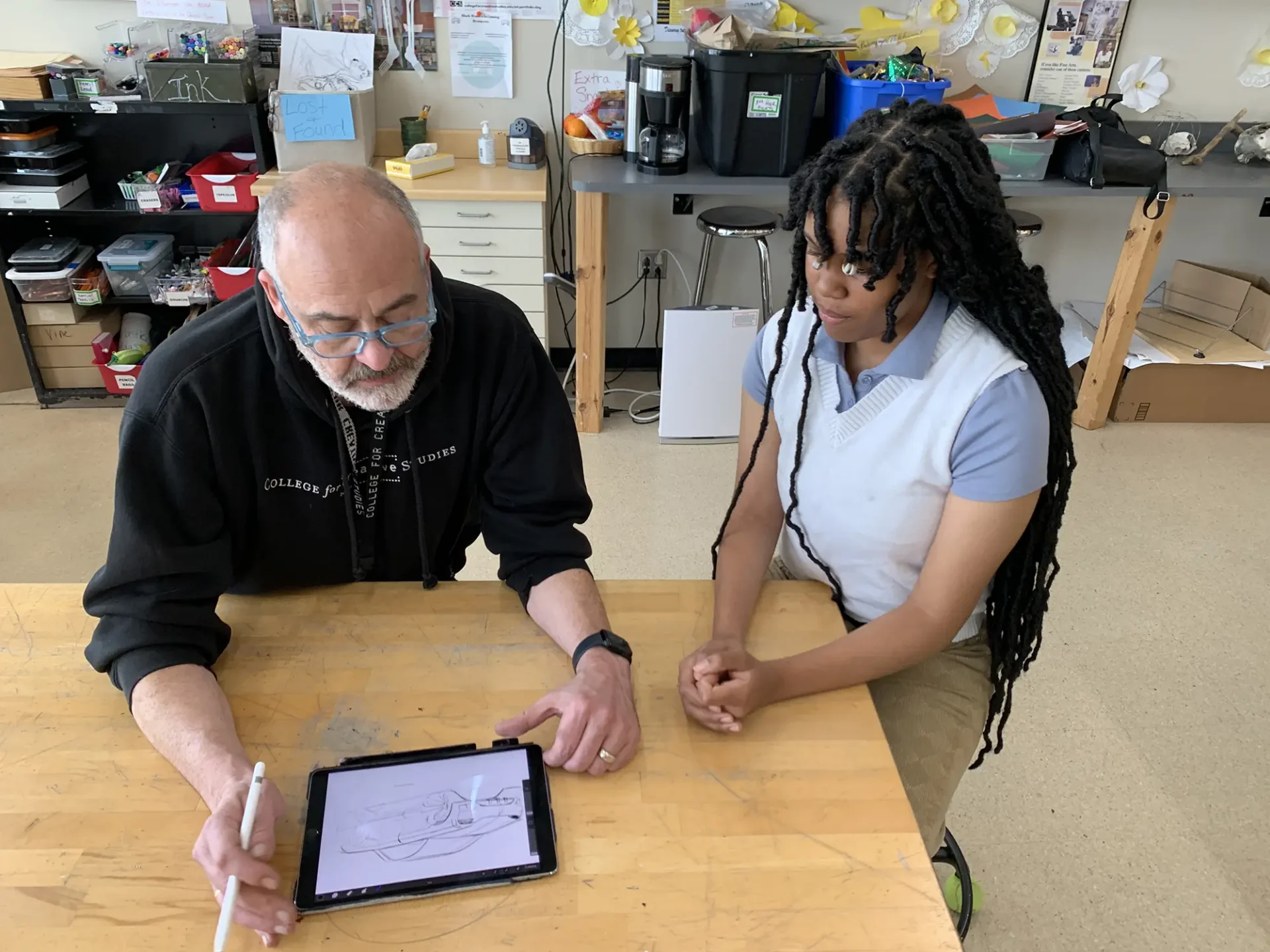 CCS faculty working with a student showing how to draw a vehicle.