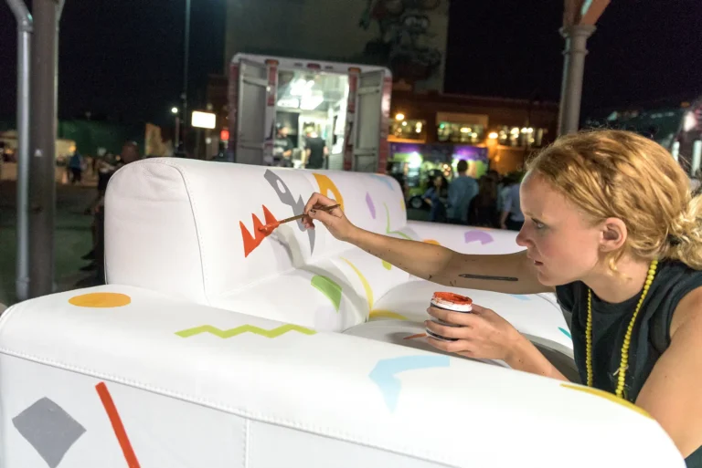 A woman painting a white couch with design elements.