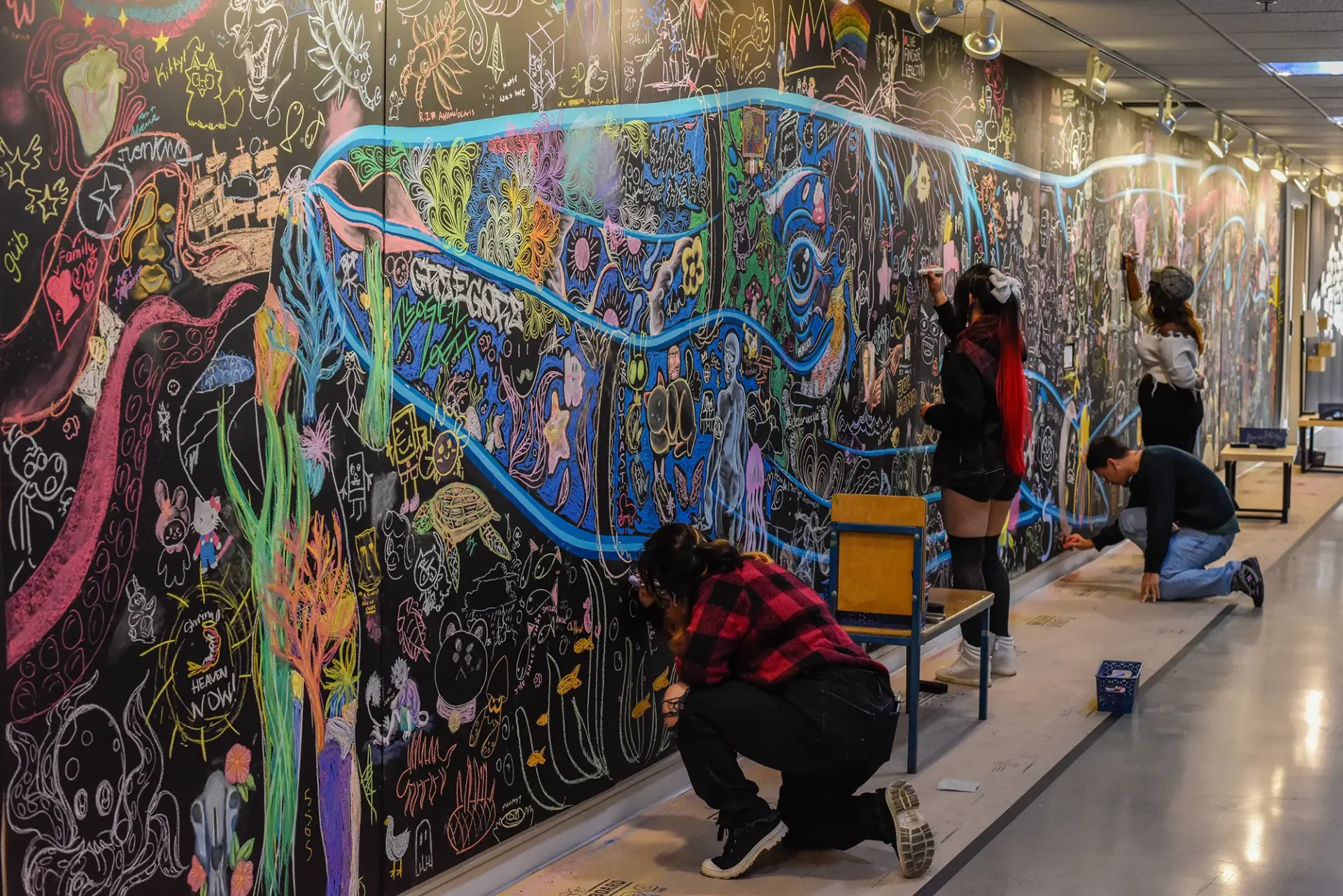 CCS students drawing with chalk on an on-campus mural.