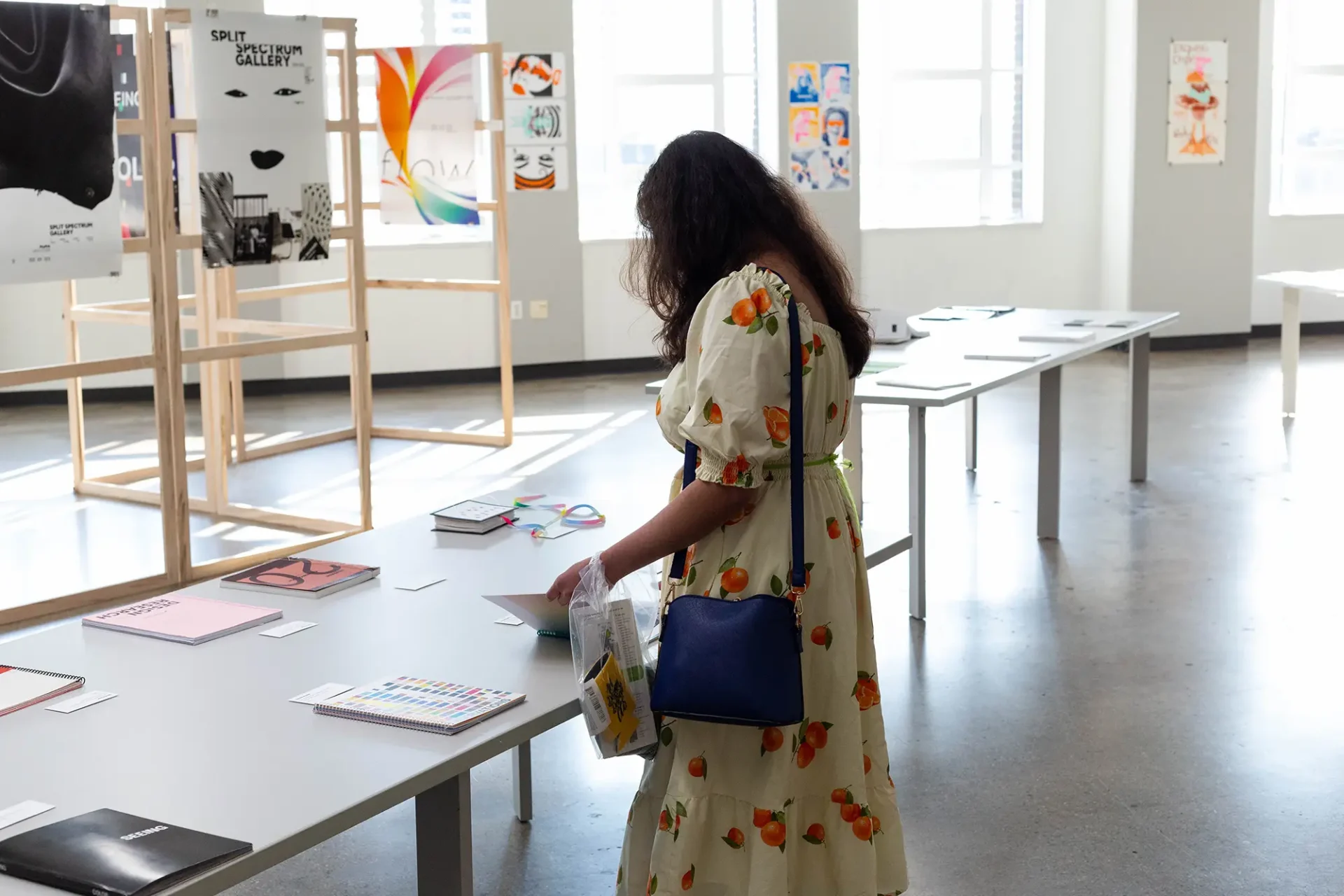 A visitor examining a book on table, surrounded by artwork