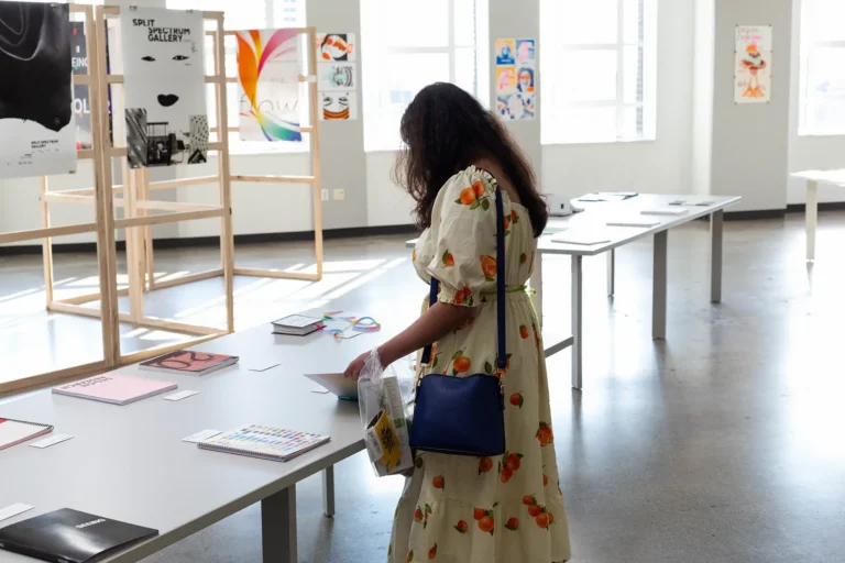 A visitor examining a book on table, surrounded by artwork