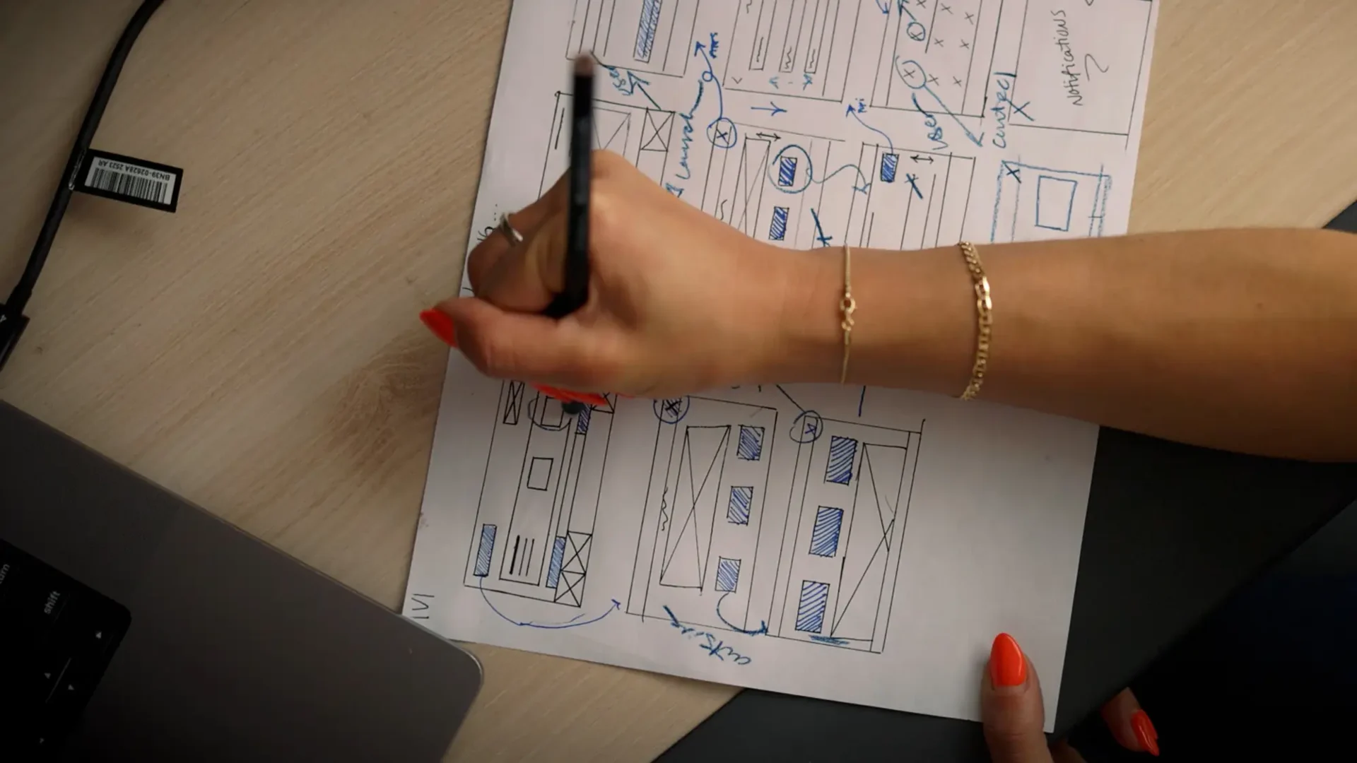 Top-down view of UX Design alum Christine Montalbano drawing website wireframe sketches and UI layouts on paper with a pen.