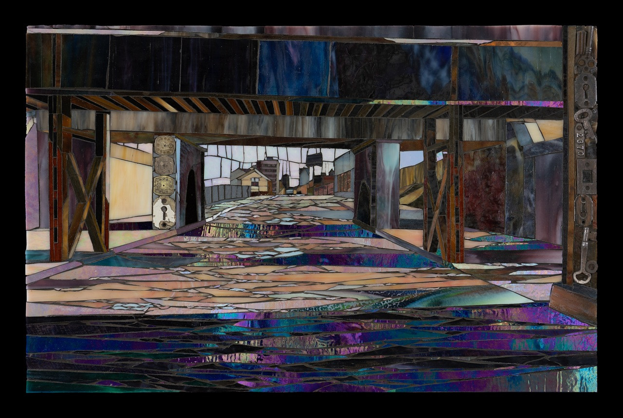 Stained glass mosaic artwork depicting an urban streetscape viewed through the dark structure of an overpass or bridge.