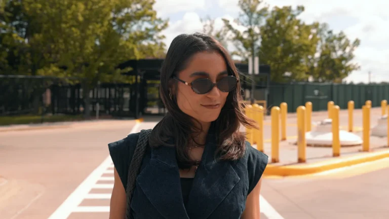 UX Design alum Christine Montalbano walking into Stellantis Headquarters wearing a denim shirt and sunglasses