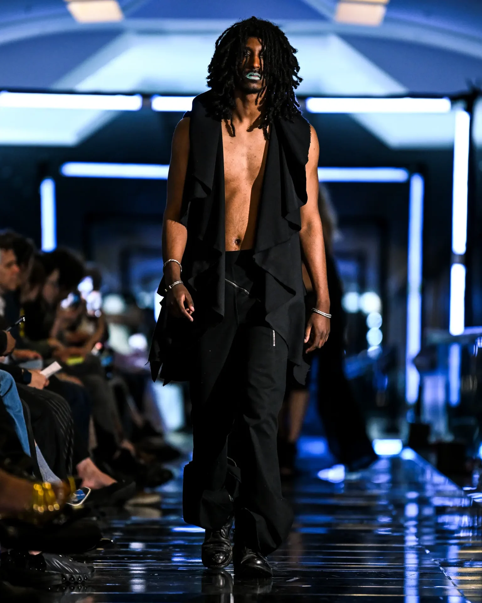 Model walking the runway wearing an all black layered outfit.