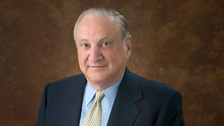 Headshot of Richard Manoogian in a dark suit, light blue shirt, and patterned gold tie.