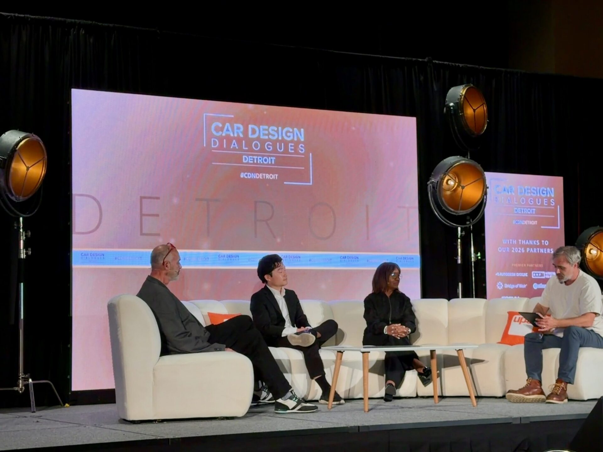 Four panel guests—Paul Snyder, Jason Song, Crystal Windham, and James McLachlan—sit on a stage couch during Car Design Dialogues Detroit event.