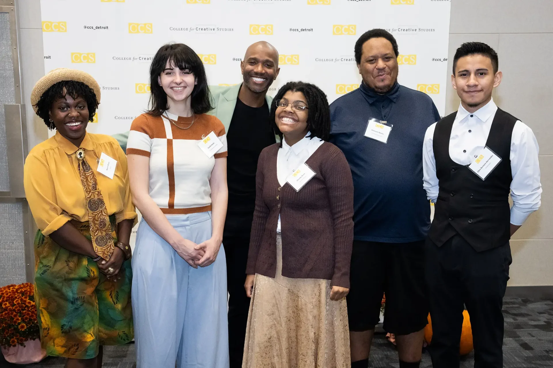 A group of six people posing together and smiling in front of a College for Creative Studies step-and-repeat backdrop.