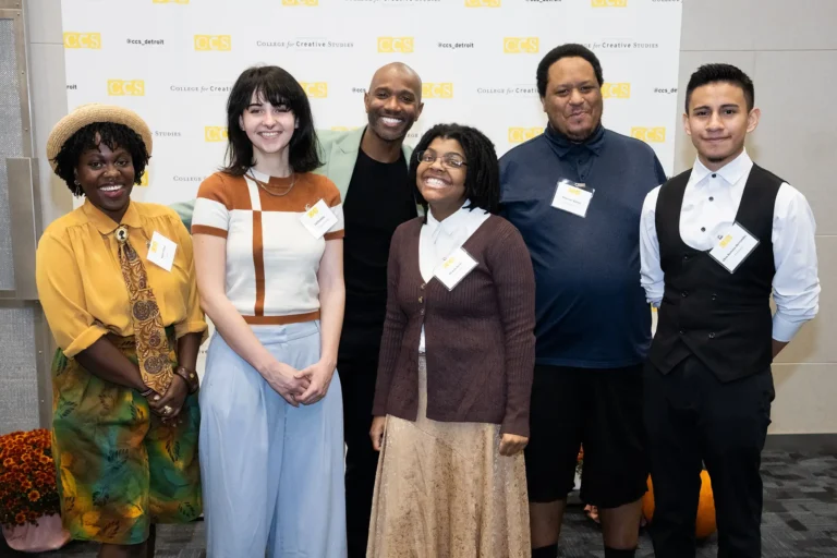 A group of six people posing together and smiling in front of a College for Creative Studies step-and-repeat backdrop.